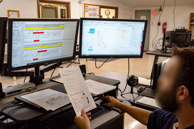Inmate transcribing braille on two monitors