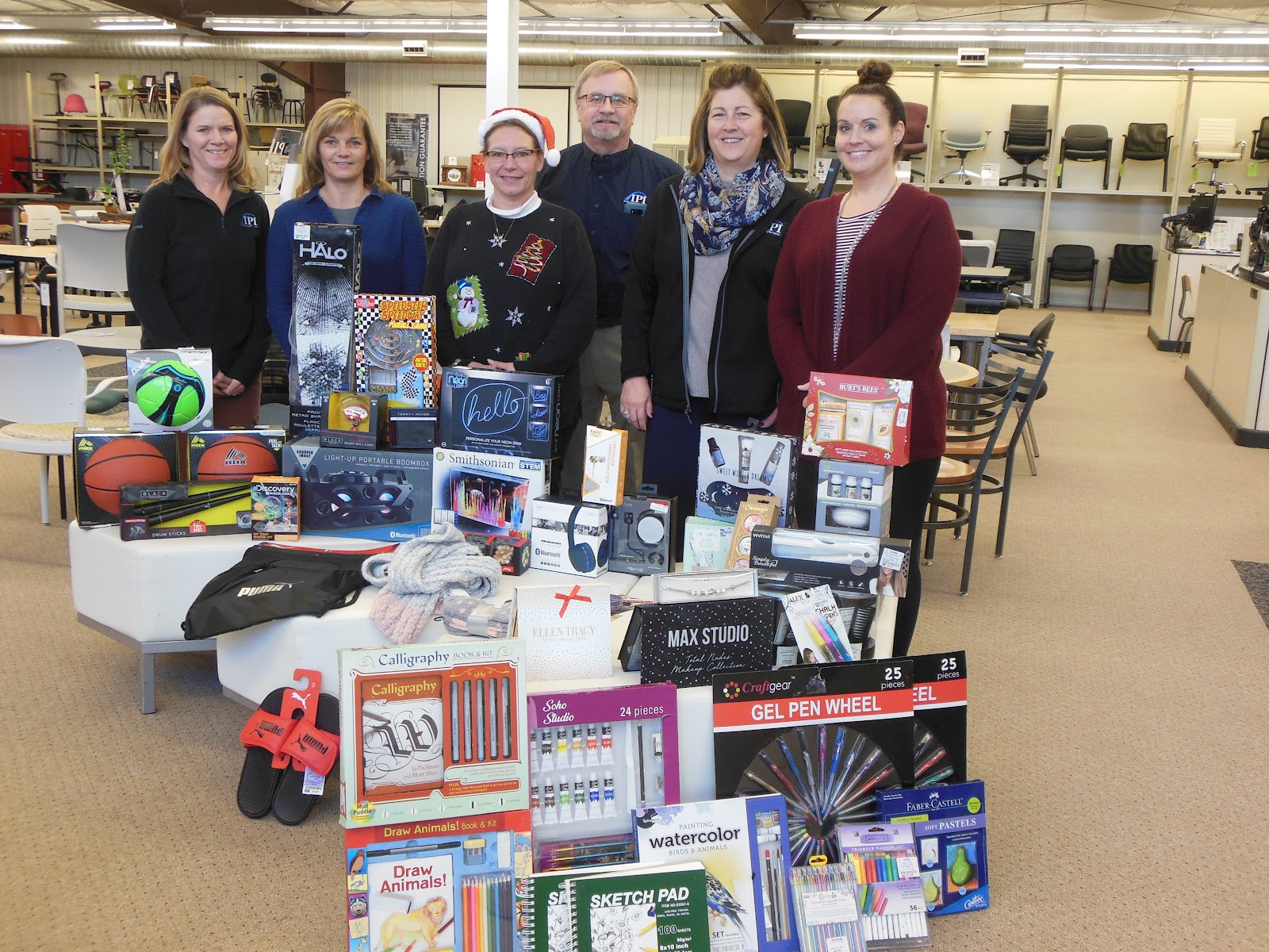 IPI's Showroom staff gathered around a large stack of toys and games to be donated
