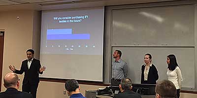 Four Iowa State University MBA students giving a slideshow presentation in front of an audience.