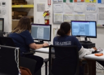 Two incarcerated women in IPI's imaging program working at their desks