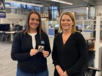 Ann Baughman standing next to Sara Schnotala who is holding her IPI challenge coin in both hands.